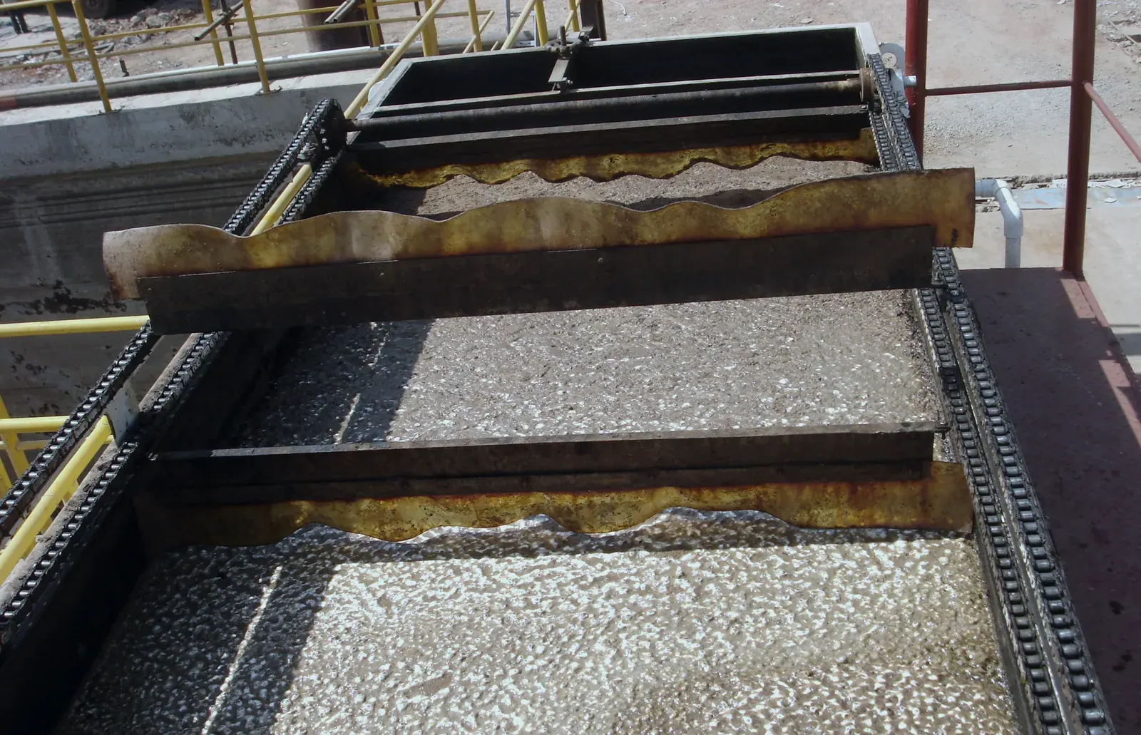 Looking down into a dissolved air flotation unit: a floating layer, scraper flights on chains, and a beach plate at the far end.