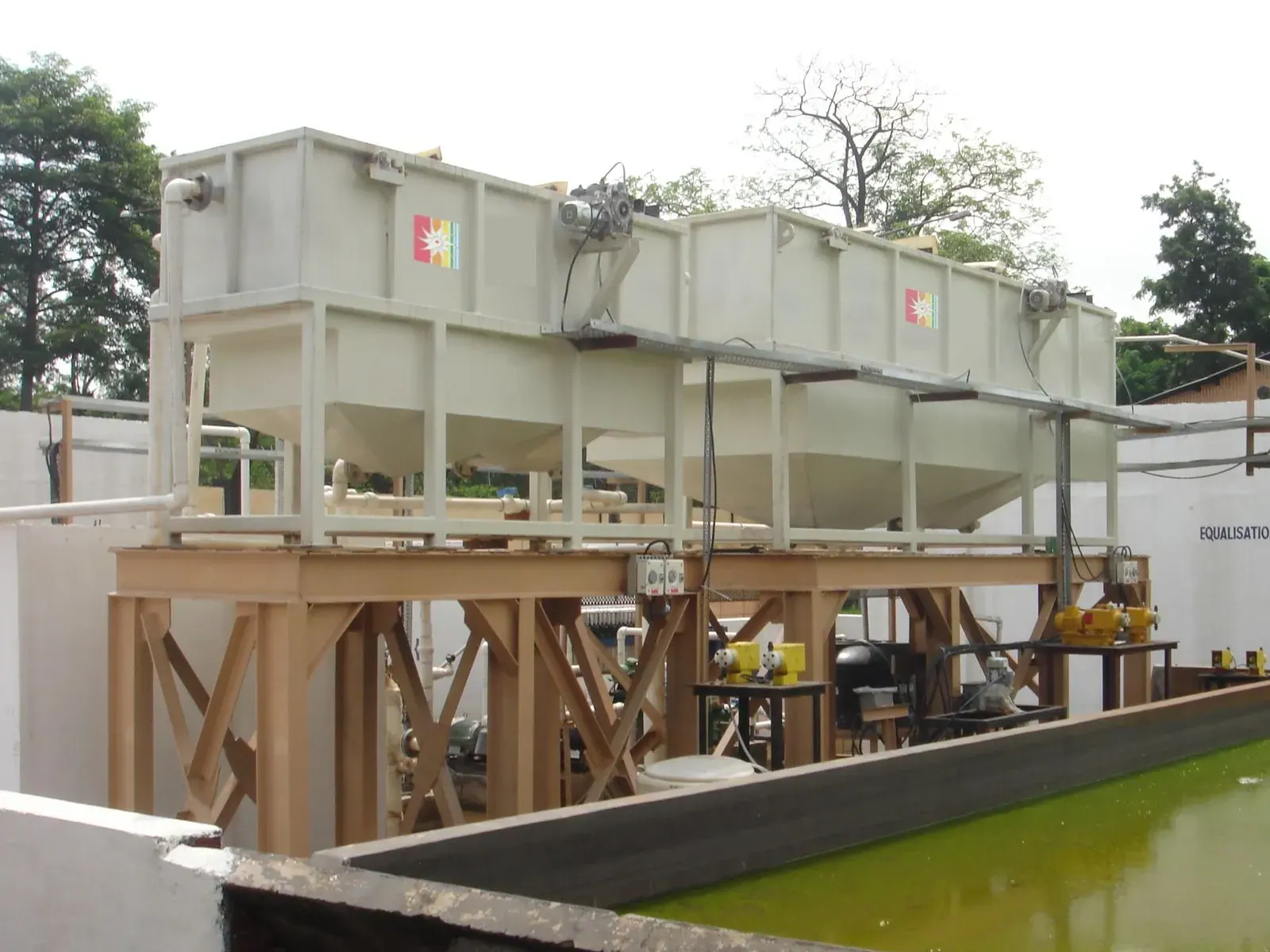 A dissolved air flotation unit on a timber platform beside an open equalisation tank.